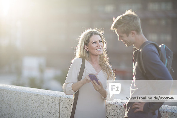 Man and woman with cell phone talking in the city