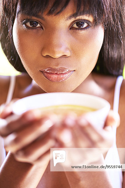 Porträt einer Frau  die eine Schale Tee mit Orangenscheibe hält.