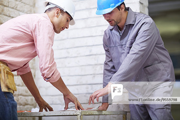 Construction worker and foreman dicussing building plan