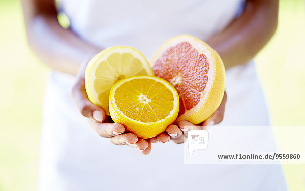 Frauenhände mit Orangen- und Grapefruithälften
