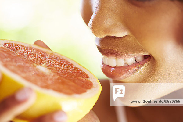 Lächelnde Frau hält die Hälfte der Grapefruit Nahaufnahme