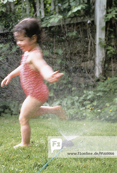 Blurred View of Girl in Swimwear Playing in Sprinkler