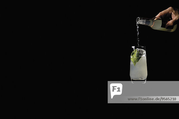 Handgegossener Cocktail in Glas über schwarzem Hintergrund