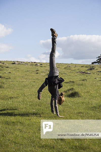 Full length side view of woman performing handstand on field