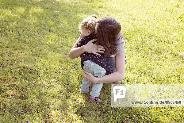Mother embracing baby girl outdoors