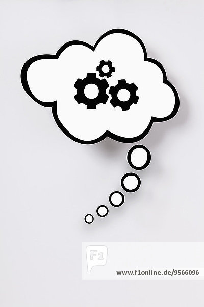 Thought bubble with gears against gray background