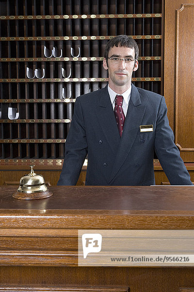 Hotel clerk standing behind desk in hotel reception