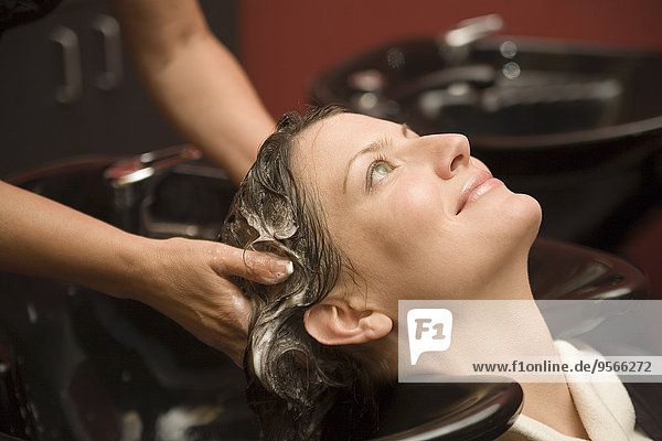 Eine junge Frau  die sich in einem Salon die Haare waschen lässt.