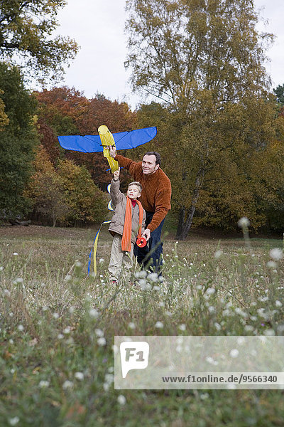 Father and son launching a kite together in a park
