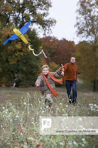 Vater und Sohn beim Drachenfliegen im Herbst