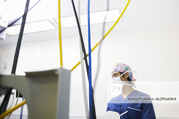 Junge Krankenschwester kontrolliert medizinische Geräte während der Operation