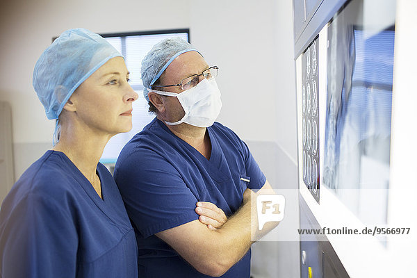 Zwei Ärzte besprechen vor der Operation das Röntgenbild und die Kernspintomographie des Patienten.