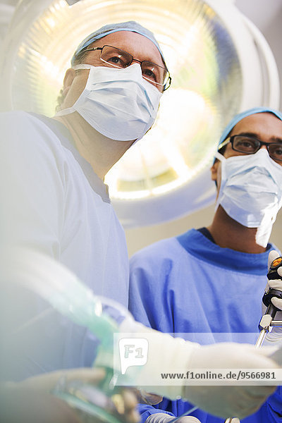 Niederwinkelansicht von reifen Ärzten, die eine Operation durchführen