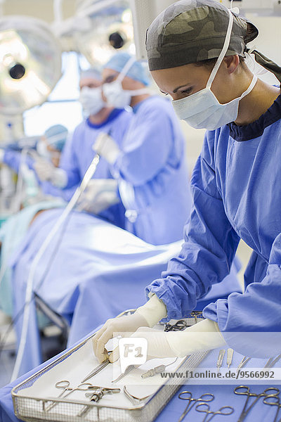 Krankenschwester steht mit chirurgischem Werkzeug im Operationssaal bereit