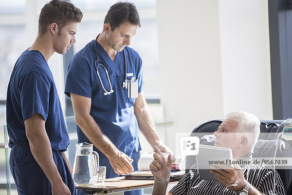 Patient mit Tablet-PC und Gespräch mit Ärzten im Krankenhaus