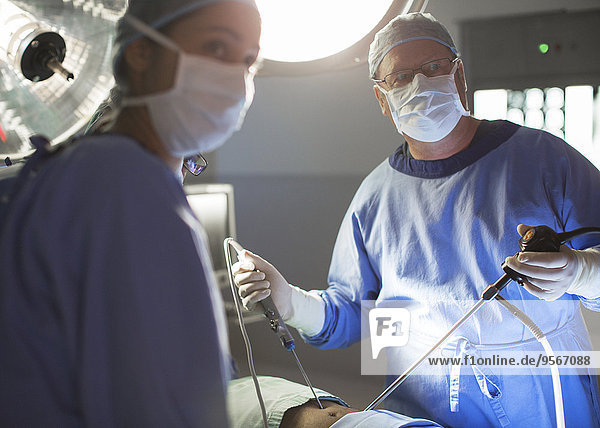 Male and female doctors performing laparoscopic surgery in operating theater