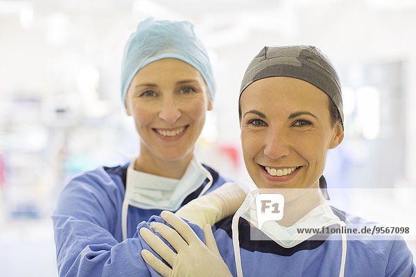Portrait of two smiling female doctors wearing surgical caps in operating theater