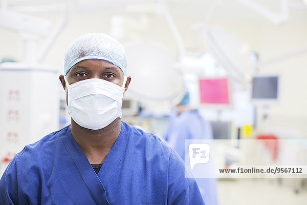 Portrait of surgeon wearing surgical mask and cap in operating theater