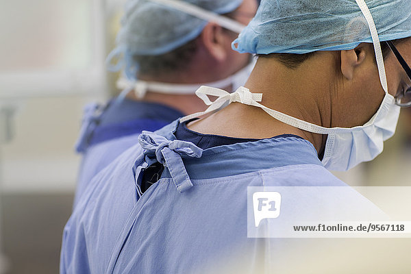 Ärzte mit OP-Kappen  -Masken und -Peelings im Operationssaal