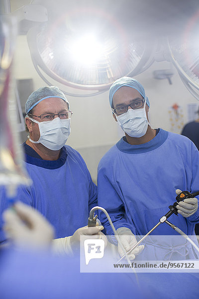 Zwei männliche Chirurgen  die eine laparoskopische Operation im Operationssaal durchführen.