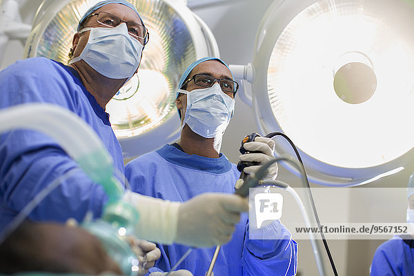 Low angle view of two surgeons holding laparoscopy equipment in operating theater