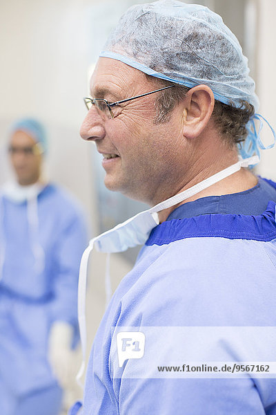 Seitenansicht des Chirurgen mit Brille  blauer OP-Kappe und Kittel
