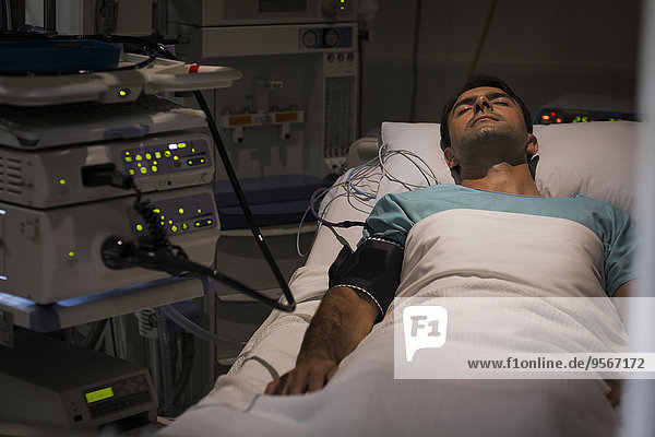 Patient lying in bed  attached to monitoring equipment in intensive care unit
