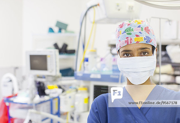 Porträt der Krankenschwester mit bunter OP-Mütze und Maske im Operationssaal