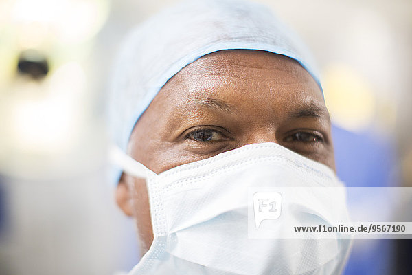 Porträt des Arztes mit OP-Haube und Maske im Operationssaal