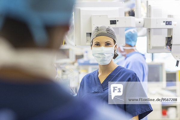 Female doctor wearing surgical cap and mask looking at camera