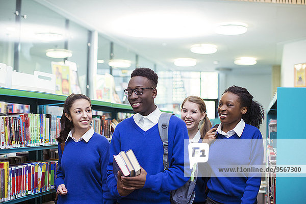 Fröhliche Schüler in blauen Schuluniformen durch die Bibliothek gehen