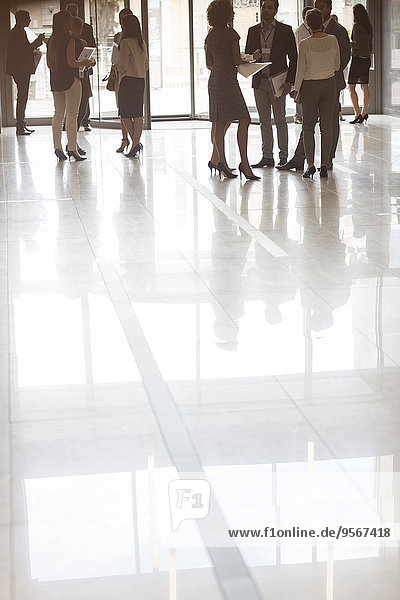 Group of business people standing in office  reflections in tiled floor