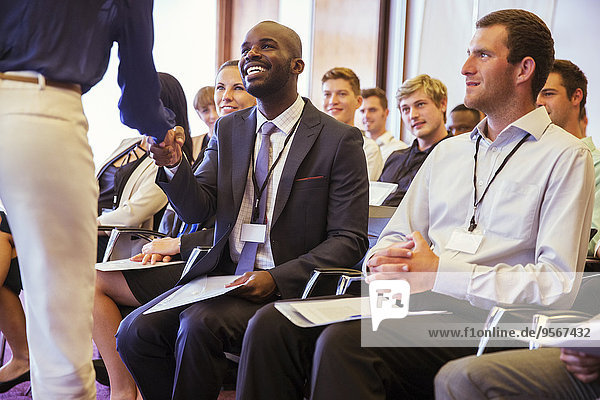 Geschäftsleute schütteln sich die Hand während eines Geschäftstreffens im Konferenzraum.