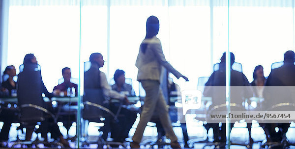 Geschäftsfrau  die während der Geschäftsbesprechung im Konferenzraum vor den Kollegen läuft.
