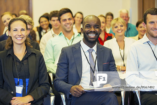 Lächelnder Geschäftsmann sitzt im Konferenzraum und schaut in die Kamera.
