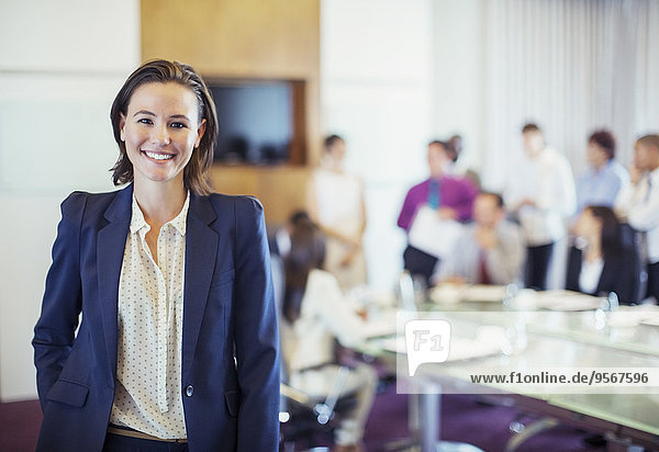 Portrait einer jungen Geschäftsfrau lächelnd im Konferenzraum  Menschen im Hintergrund
