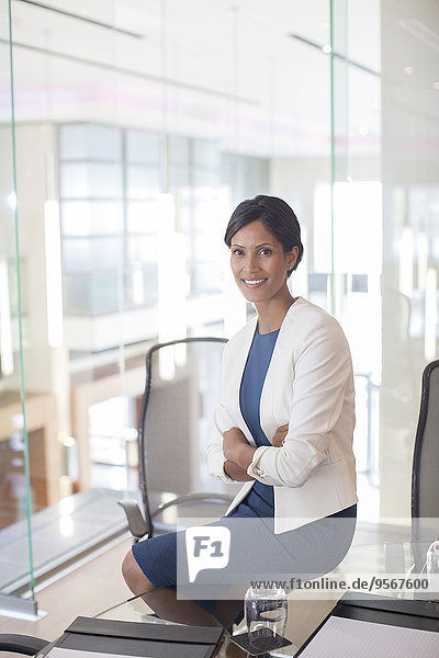 Portrait of beautiful smiling businesswoman sitting at glass table in conference room