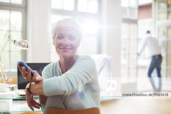 Businesswoman using cell phone at home office desk