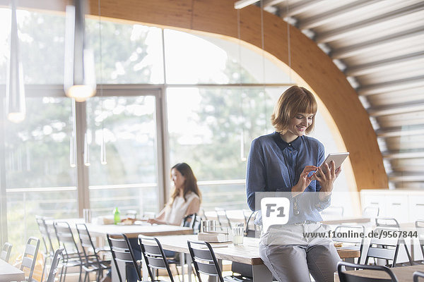 Geschäftsfrau mit digitalem Tablett in der Cafeteria