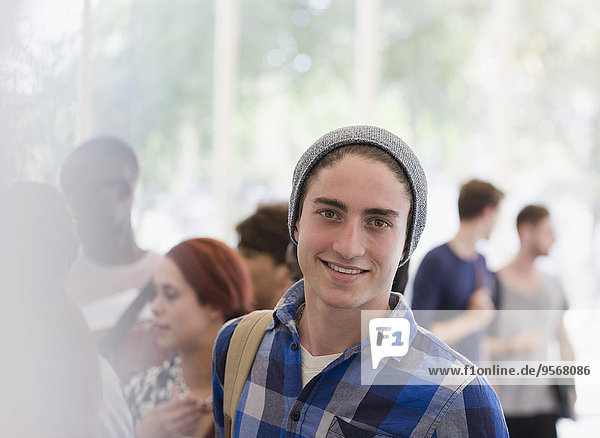 Portrait of smiling university student during break  people talking in background