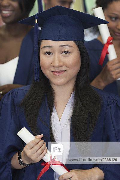 Female student smiling at camera and holding diploma
