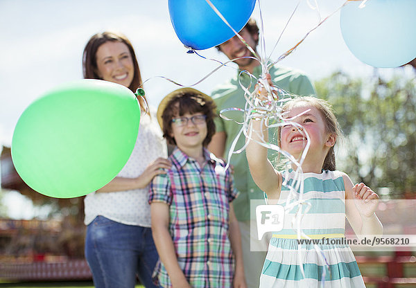 Junges Mädchen mit Luftballons,  Familie steht hinter ihr