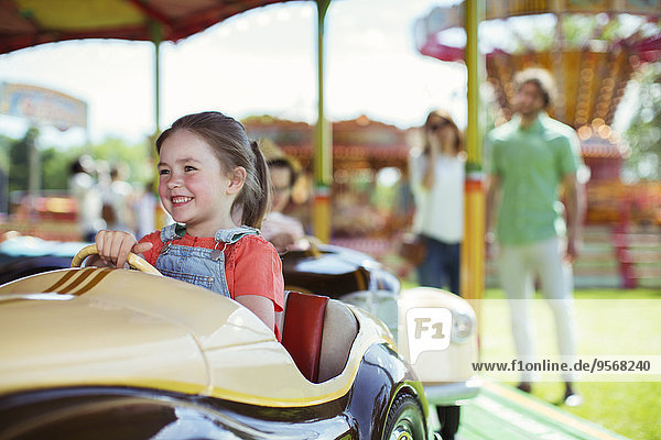 Cheerful girl on carousel in amusement park