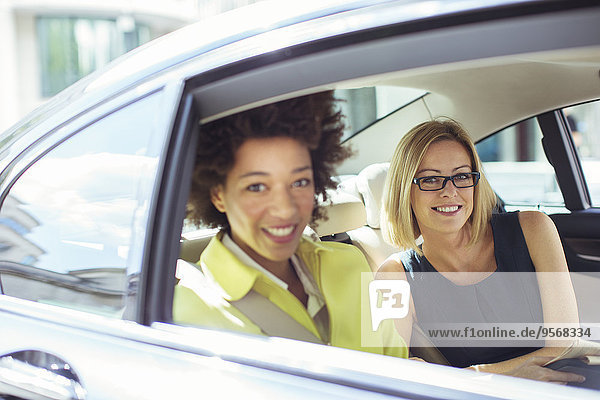 Geschäftsfrauen lächeln auf dem Rücksitz des Autos