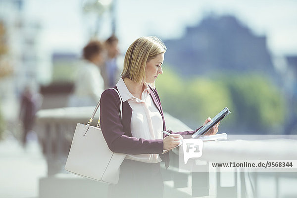 Geschäftsfrau mit digitalem Tablett am Stadtrand