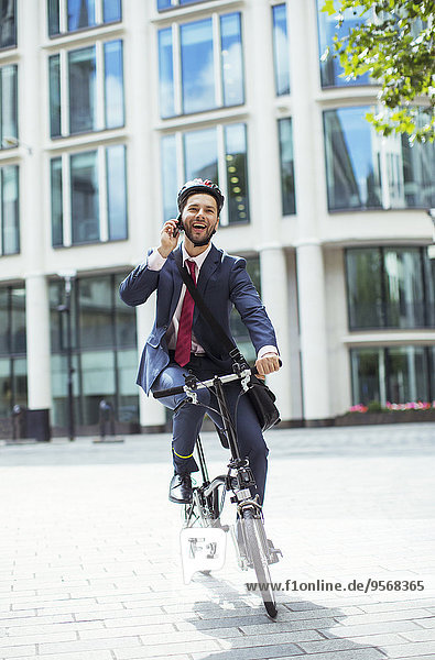 Geschäftsmann im Gespräch mit dem Handy auf dem Fahrrad