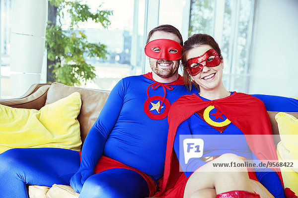 Superhero couple smiling on living room sofa