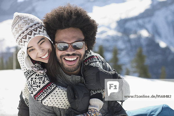 Porträt eines glücklichen Paares  das sich im Schnee umarmt.