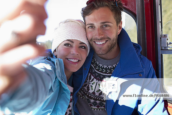 Couple talking selfie in ski lift