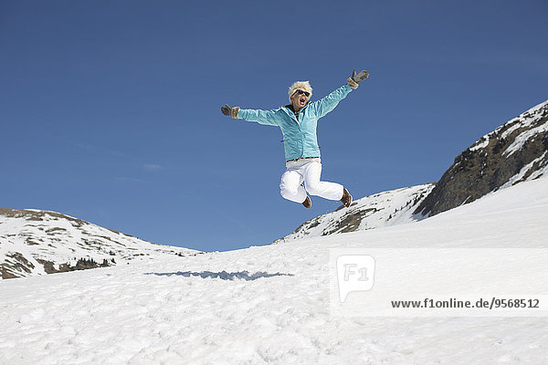 Exuberant woman jumping in snow